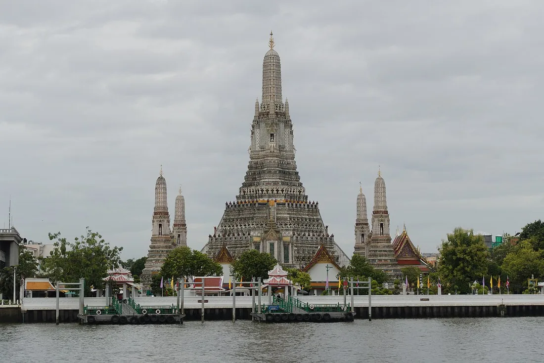 Wat Arun’s central spire and surrounding towers viewed across the Chao Phraya River in Bangkok.