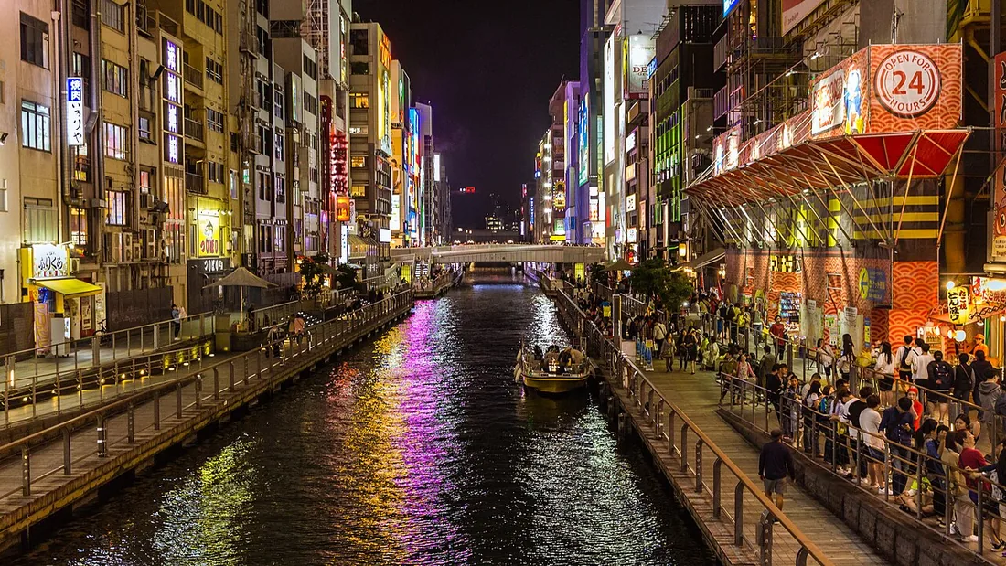 Dotonbori Canal at night, lined by illuminated signs and waterside walkways in Osaka.