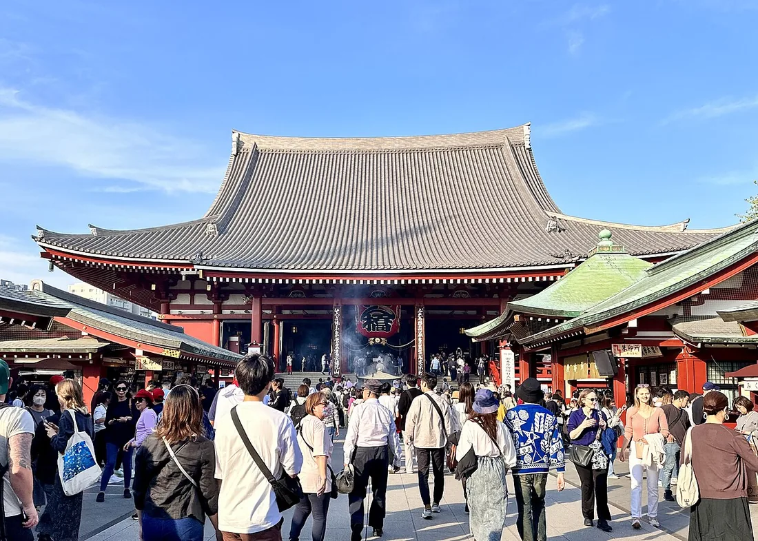 Sensoji main hall behind visitors in its courtyard in Asakusa, Tokyo.